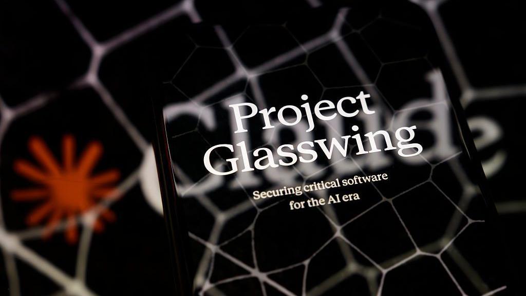 La imagen promocional del Proyecto Glasswing se muestra en la pantalla de un teléfono inteligente colocado sobre una superficie reflectante sobre la cual se proyecta un logotipo de Claude con patrones hexagonales, en Créteil, Francia, el 8 de abril de 2026.