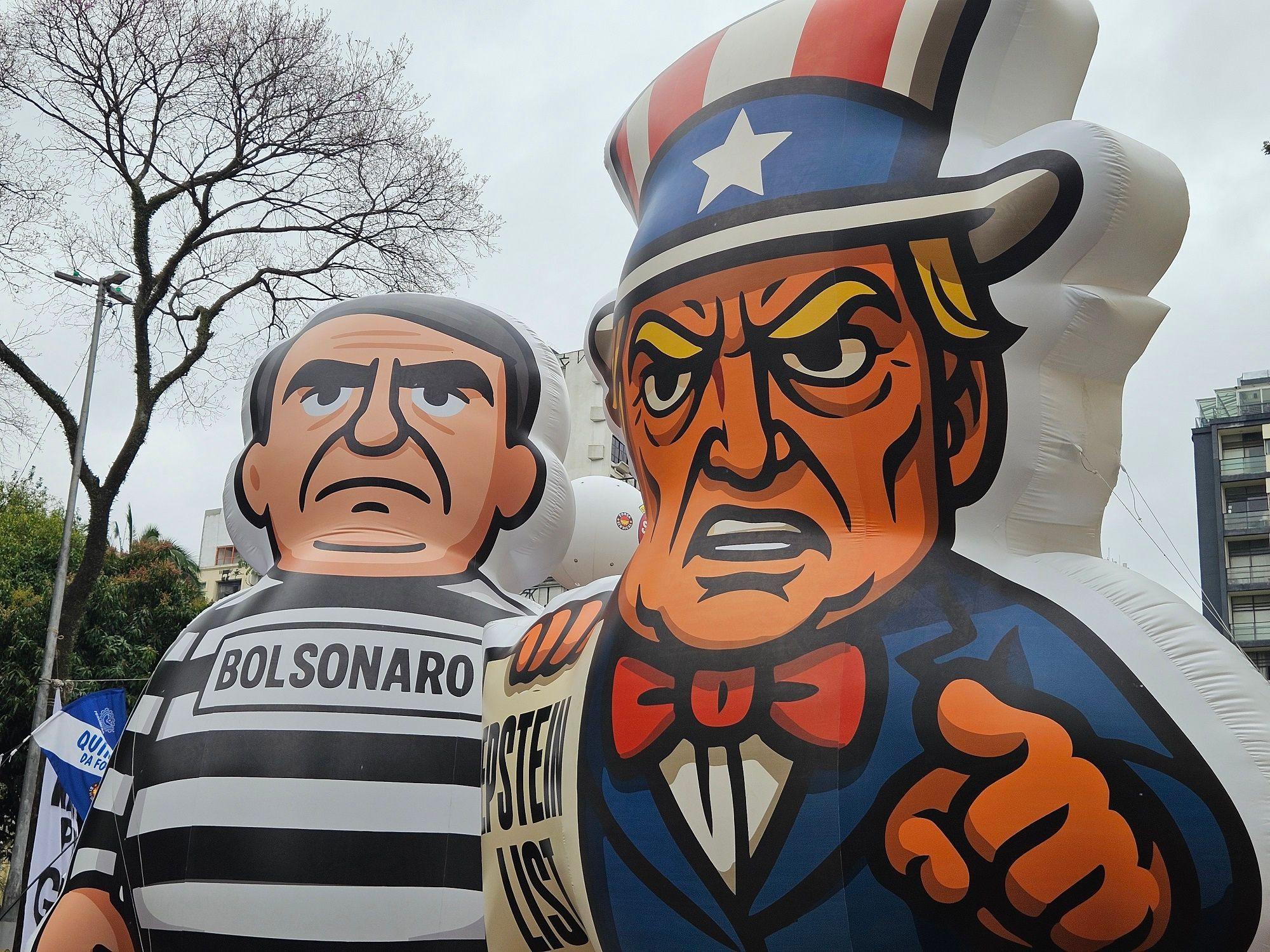 Bonecos infláveis de Jair Bolsonaro, vestindo roupa de presidiário, e de Donald Trump, segurando um cartaz onde se lê 'Epstein list