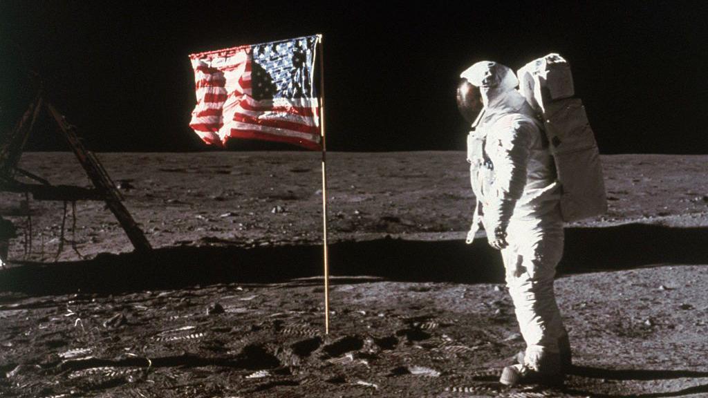 O astronauta Buzz Aldrin, de p&eacute;, ao lado de uma bandeira dos Estados Unidos colocada na Lua, durante as atividades extraveiculars da Apollo 11, em 1969 