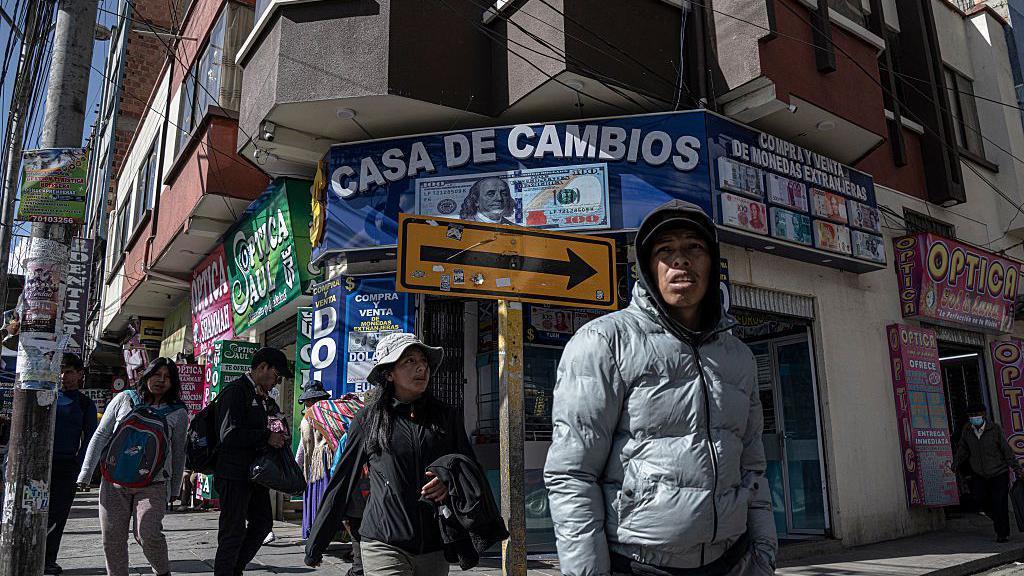 Personas caminan frente a casas de cambio en el centro de El Alto, Bolivia, el jueves 14 de agosto de 2025. 