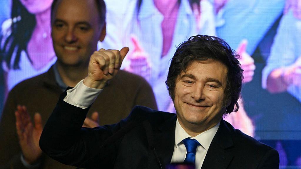 Adorni está detrás de un Milei sonriente