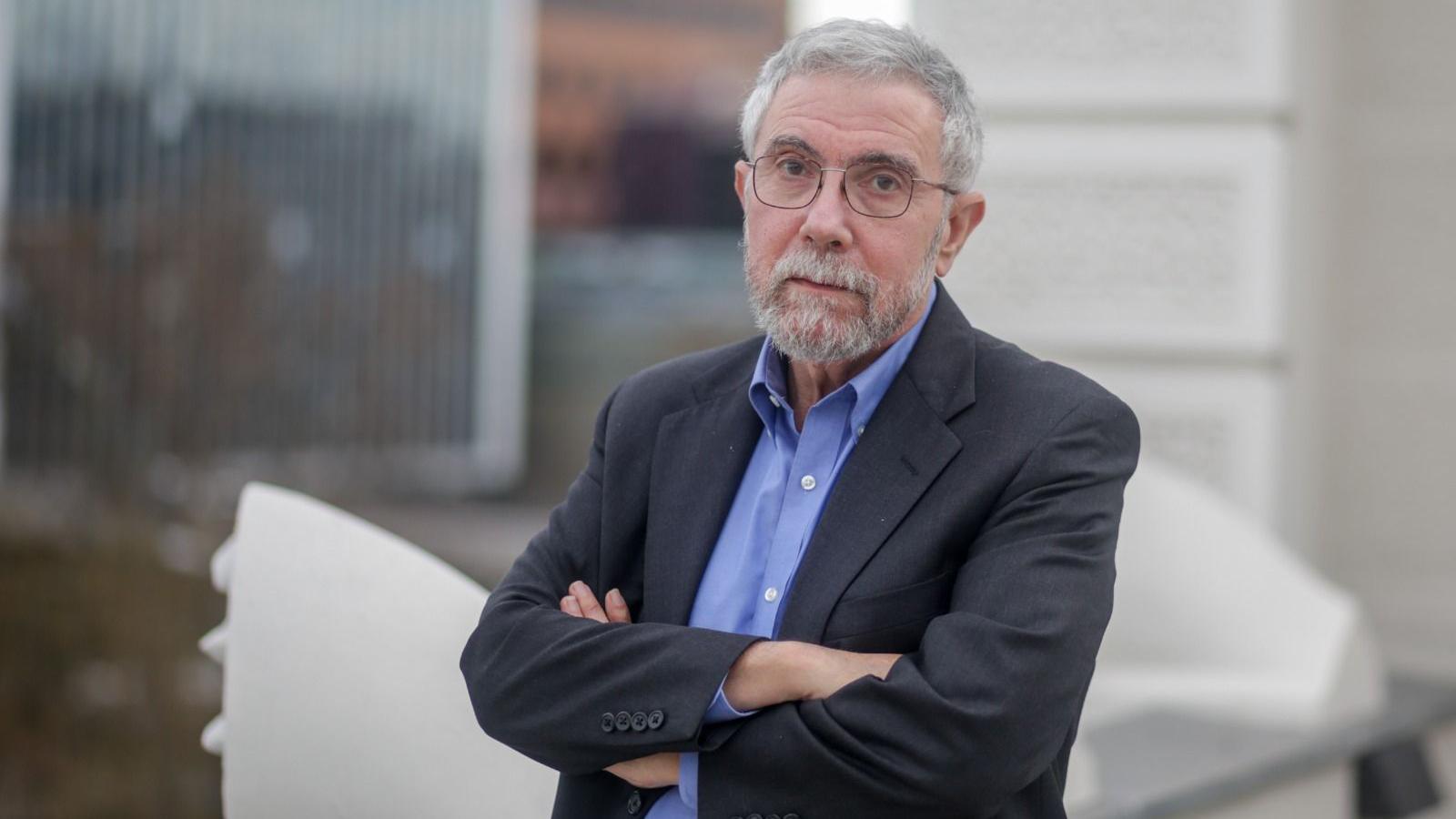 Foto colorida mostra o economista americano Paul Krugman, um homem branco de barba e cabelos brancos, por volta de 70 anos, usando óculos e um terno e com os braços cruzados