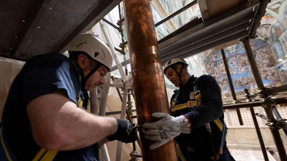 Dos hombres trabajan en el montaje de una tubería