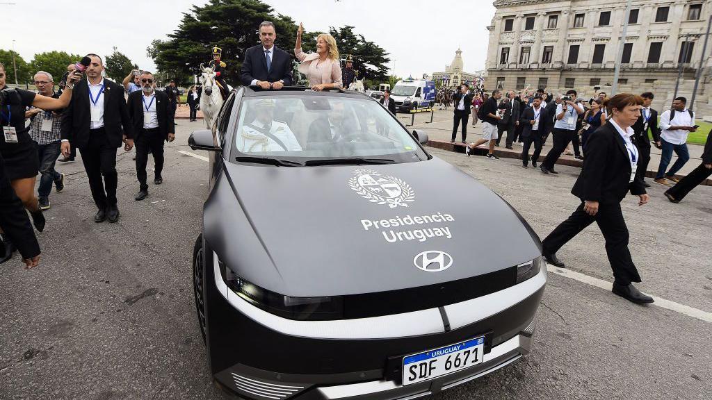 El presidente uruguayo Yamandú Orsi asume el cargo junto a su vicepresidenta Carolina Cosse parado en un auto eléctrico frente al Palacio Legislativo de Montevideo.