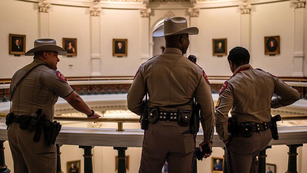 Tres agentes del Departamento de Seguridad de Texas, de espaldas en el Capitolio estatal.