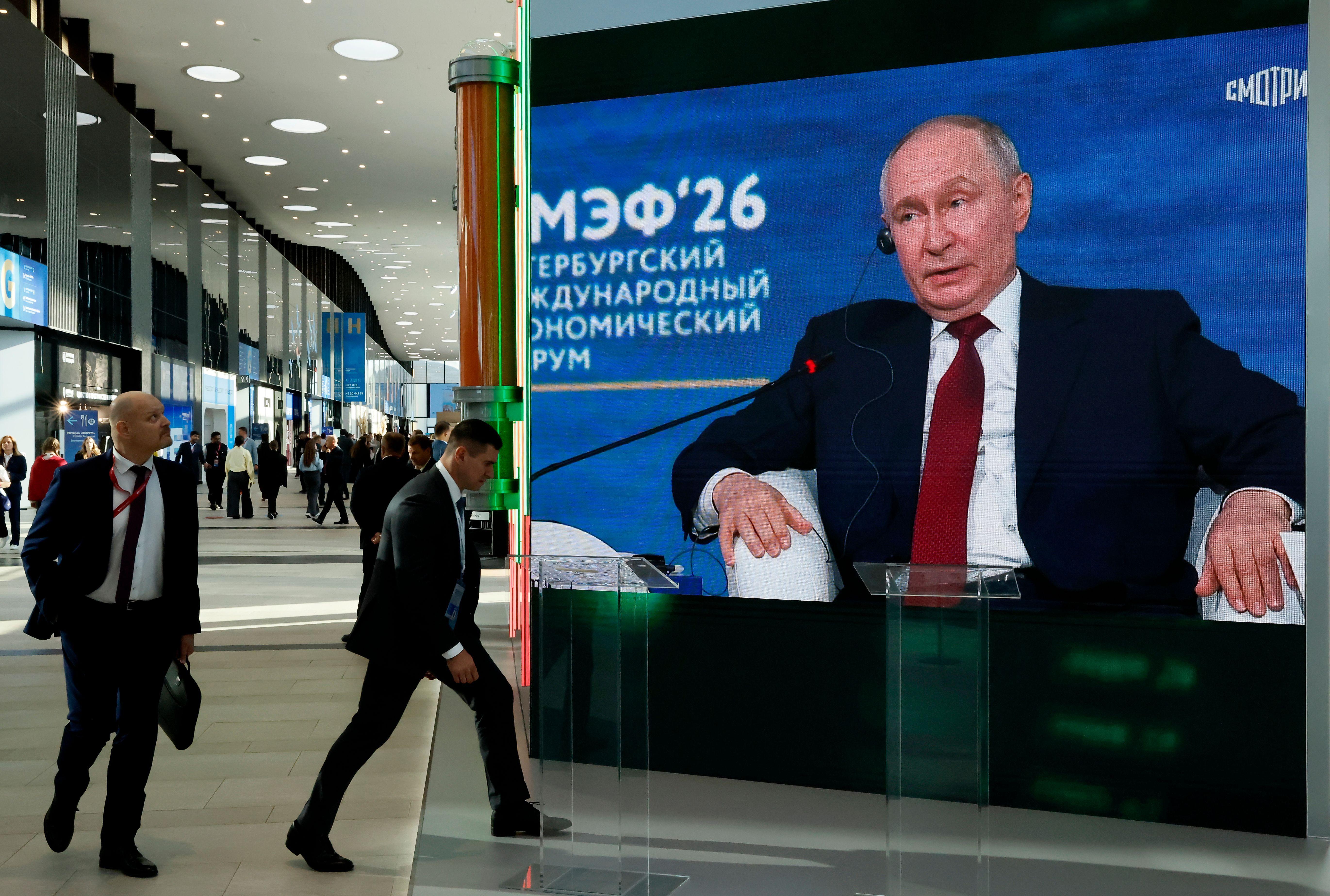 Personas pasan por delante de una pantalla en la que se ve a Putin en el foro económico de San Petersburgo.