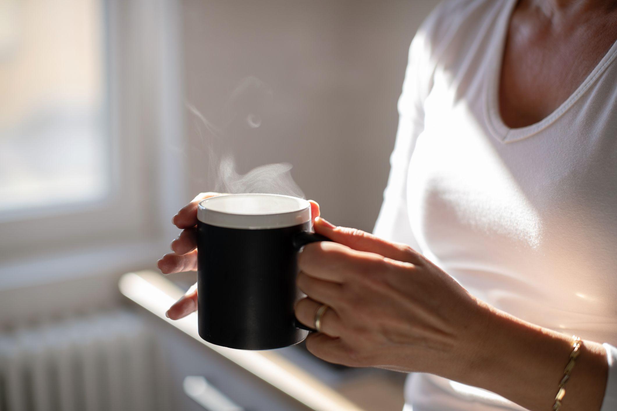 একজন নরারী একটি মগ ধরে আছেন যেটি থেকে ধোঁয়া বের হচ্ছে