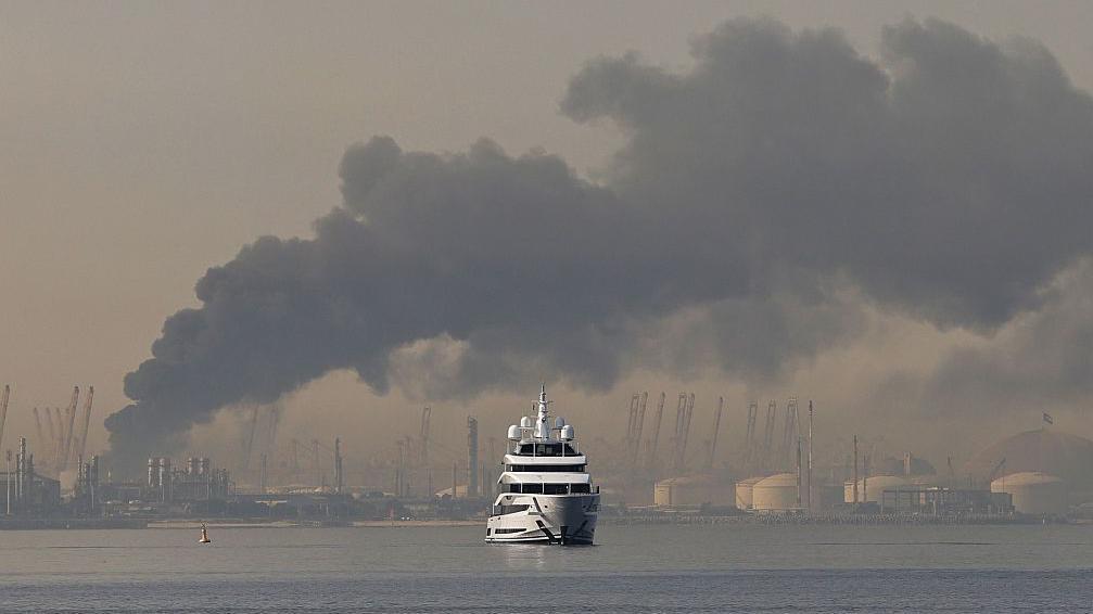 Jahta plovi pored stuba dima koji se diže iz luke Džebel Ali posle iranskog napada u Dubaiju 1. marta 2026. godine