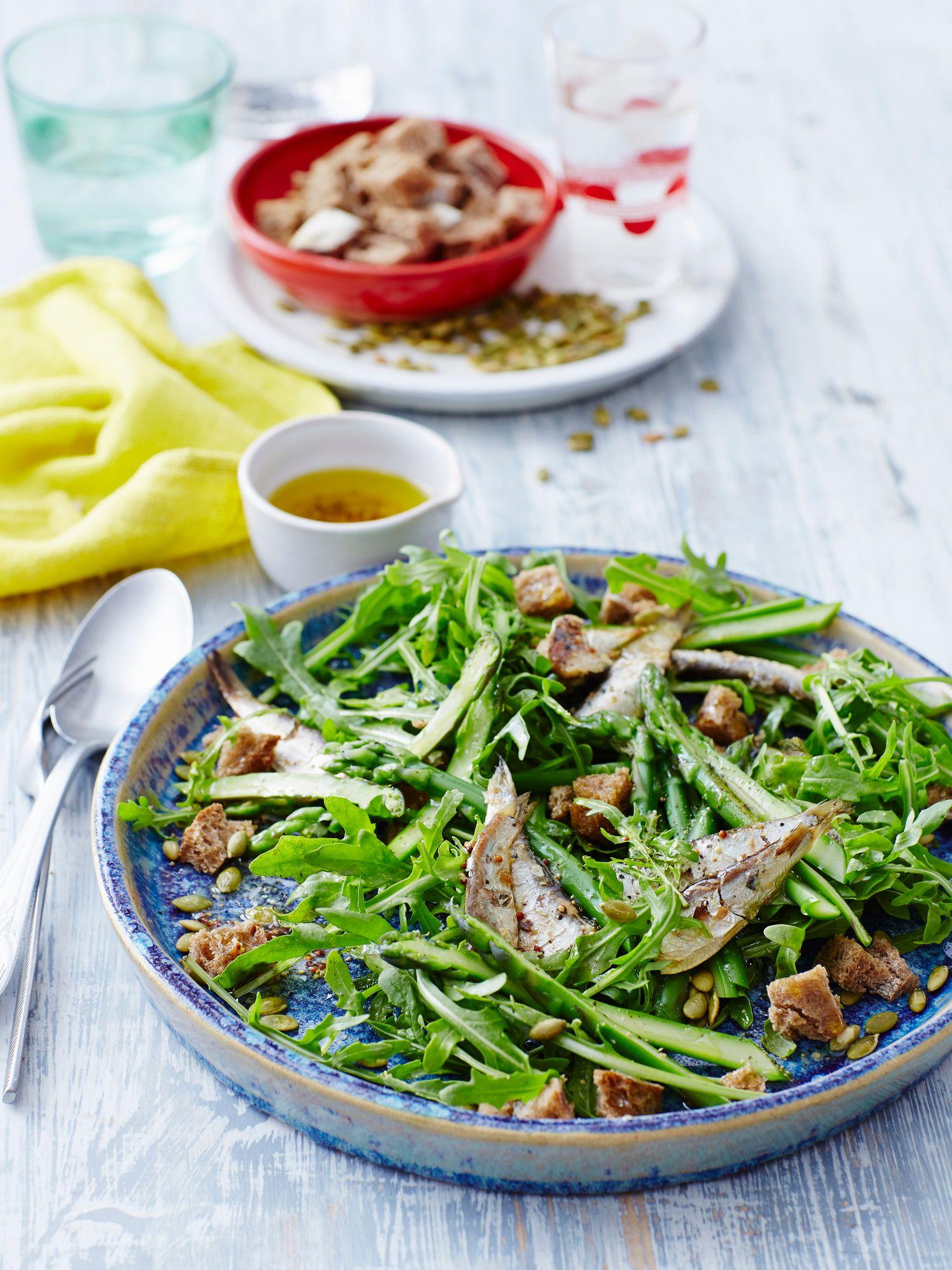 Una ensalada con sardinas y crutones, servida en un plato azul