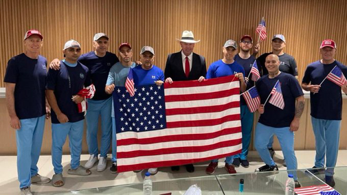 10 estadounidenses liberados en un canje de prisioneros con Venezuela posan con la bandera de EE.UU. 