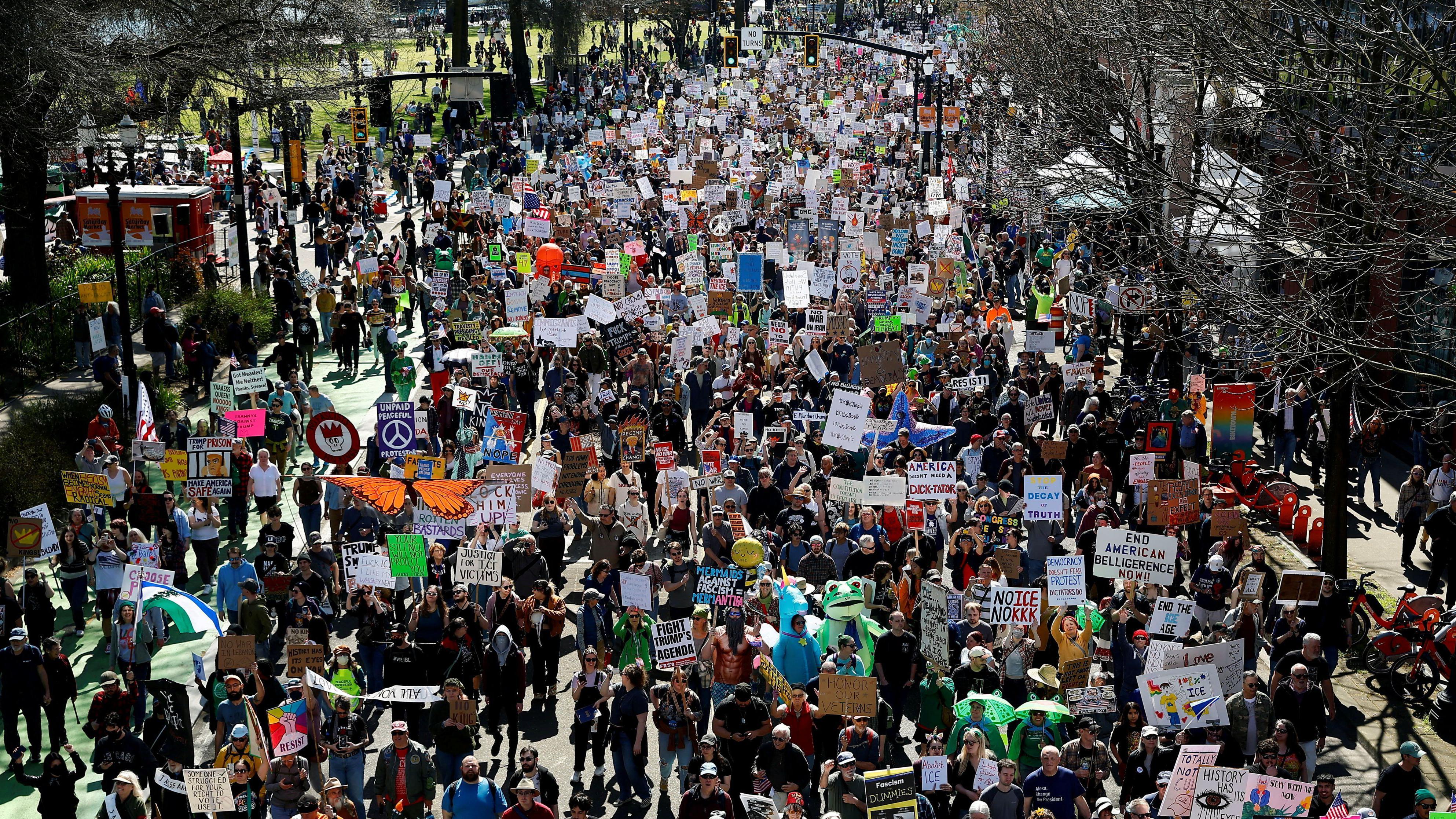 Manifestantes seguram cartazes enquanto marcham pela Naito Parkway durante um protesto &ldquo;No Kings&rdquo; contra as pol&iacute;ticas do governo do presidente dos EUA, Donald Trump, em Portland, Oregon, em 28 de mar&ccedil;o de 2026.

