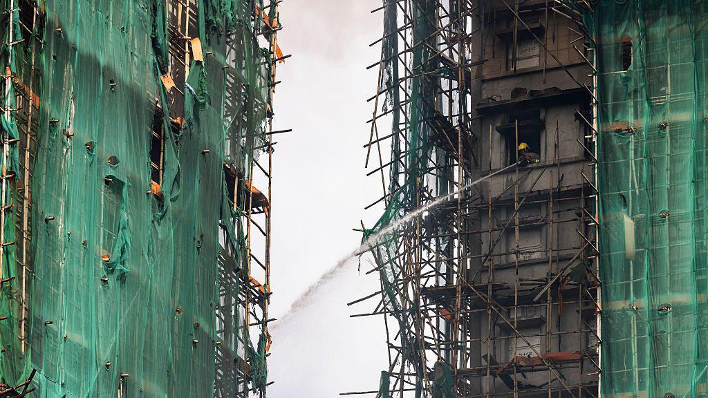 2025年11月27日，香港大埔區宏福苑，一名消防員正用水槍撲滅仍在燃燒的住宅大樓。