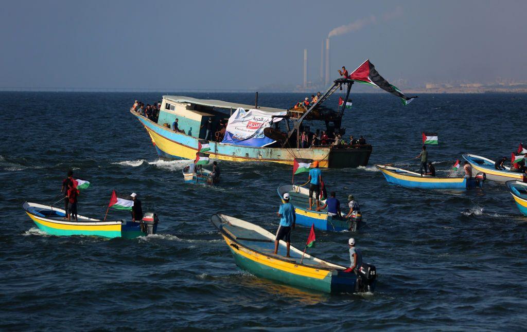 Pequeños barcos de pesca con banderas palestinas en agua del mar. 