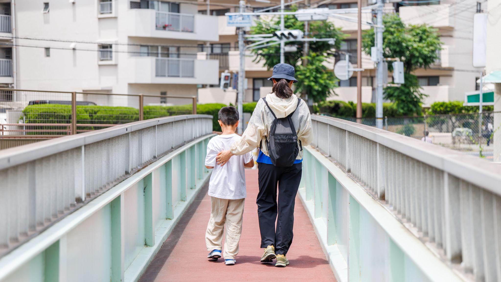 設計圖片：日本神戶一位女士（右）與男孩（左）並肩通過人行橋