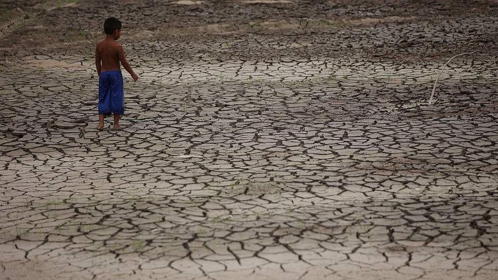 Niño parado en el lecho seco del arroyo de Igarape do Taruma, que desemboca en el Río Negro, en la Amazonía brasileña, durante la sequía de 2023 