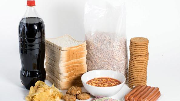 Foto com exemplos de alimentos ultraprocessados: refrigerante, batata chips, p&atilde;o de forma, macarr&atilde;o instant&acirc;neo, nuggets, cereal matinal, doces e salsichas