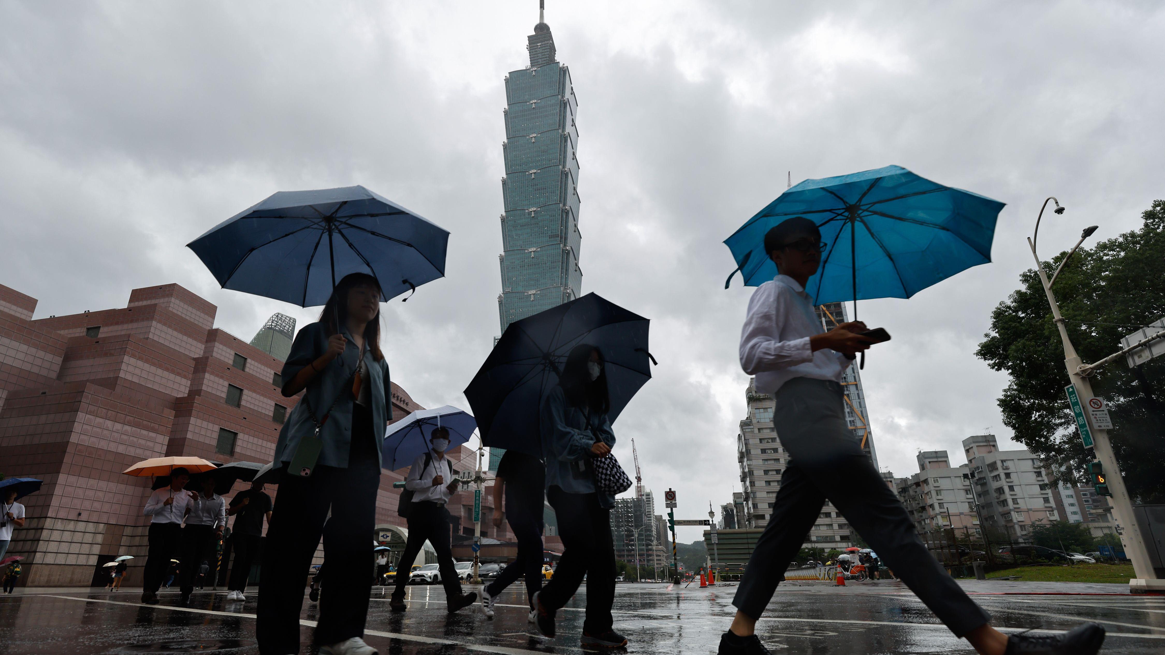台北101大樓附近民眾舉起雨傘橫過馬路（23/9/2025）