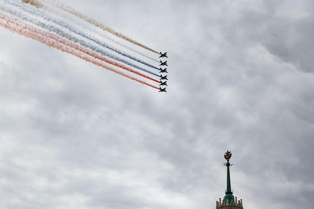 Aviones de combate rusos lanzan humo con los colores de la bandera rusa mientras sobrevuelan el centro de Moscú; en la imagen se aprecia la parte superior de la cúpula de un edificio.
