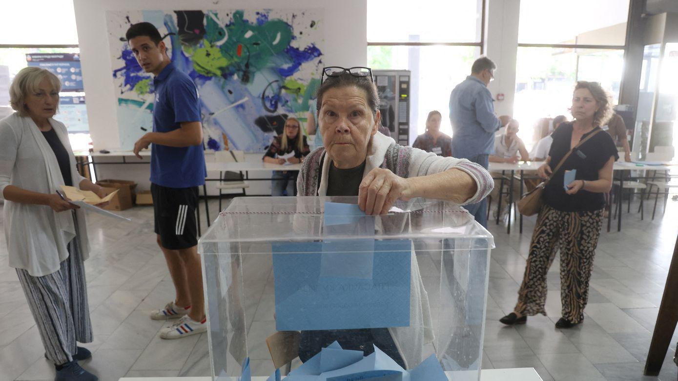 Starija žena ubacuje glasački listić u plastičnu kutiju