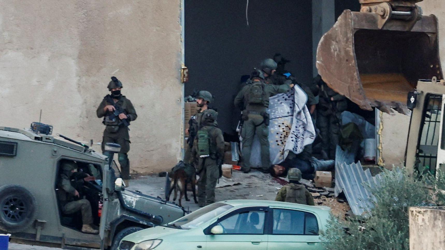 Soldados israelíes cubren con una manta los cuerpos de los palestinos tiroteados durante una redada en Yenín, en la parte de Cisjordania ocupada por Israel.