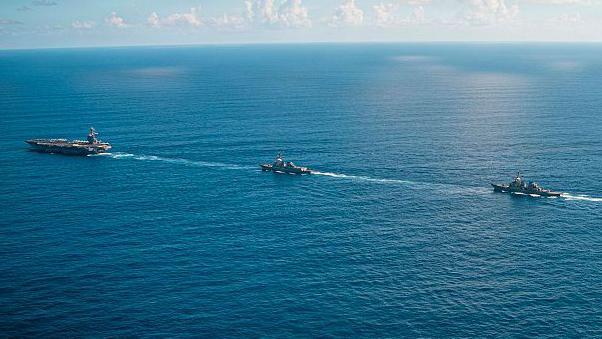 Un portaviones y dos barcos atraviesan un mar calmo.