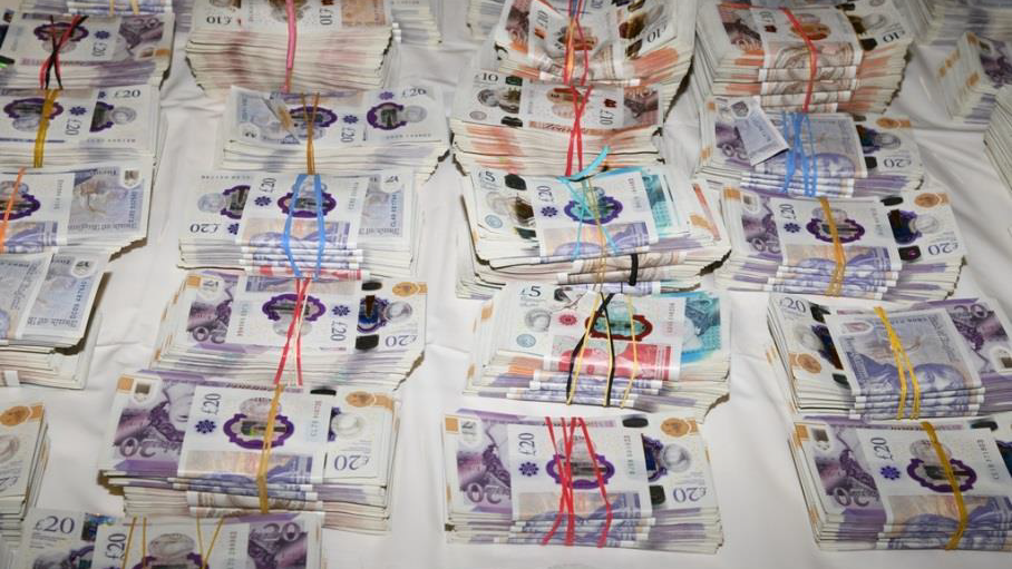 Maços de notas de libras esterlinas sobre uma superfície branca