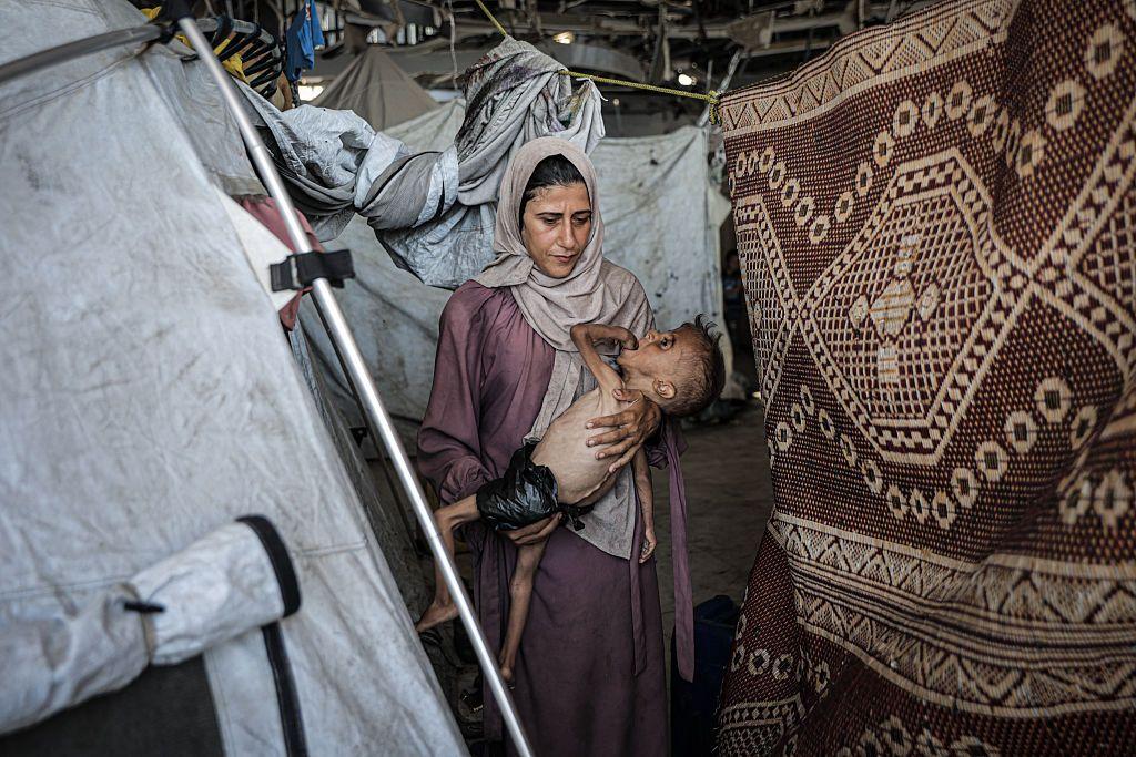 Muhammad Zakariya Ayyoub al-Matouq junto a su madre en una tienda de campaña, en Gaza. 