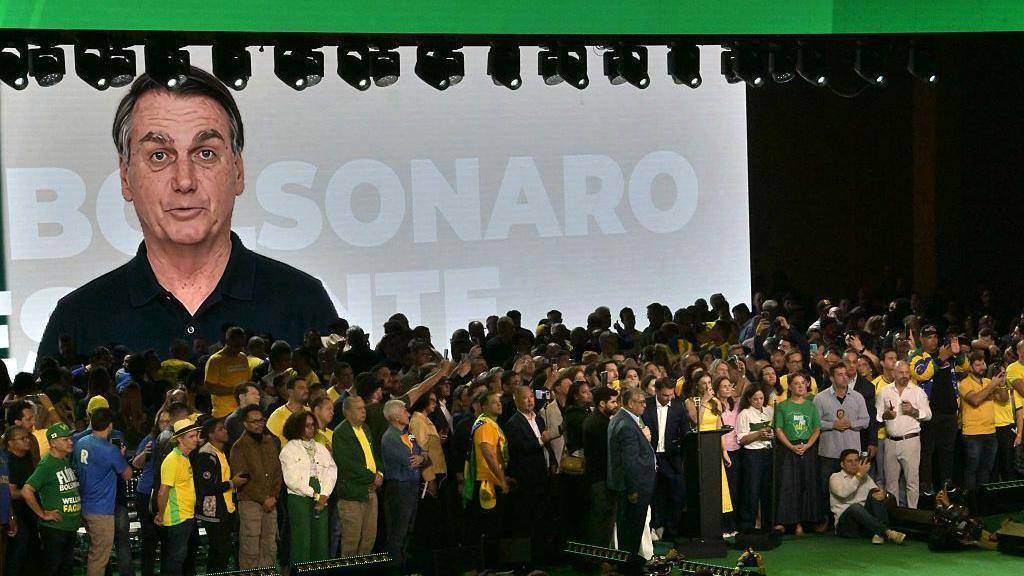 Imagem de Jair Bolsonaro no tel&atilde;o atr&aacute;s do palco.