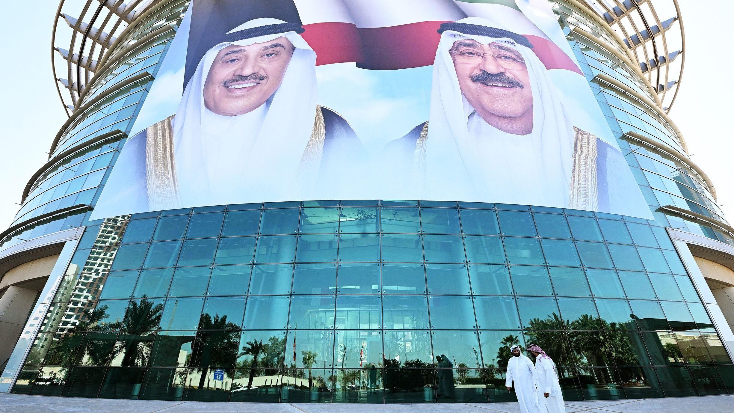 Ciudadanos kuwaitíes pasan frente a grandes retratos del emir de Kuwait, el jeque Mishal al Áhmad al Yáber al Sabah, y del príncipe heredero, el jeque Sabah al Jalid al Sabah, exhibidos en la fachada del Instituto de Diabetes Dasman en Ciudad de Kuwait el 10 de marzo de 2026.