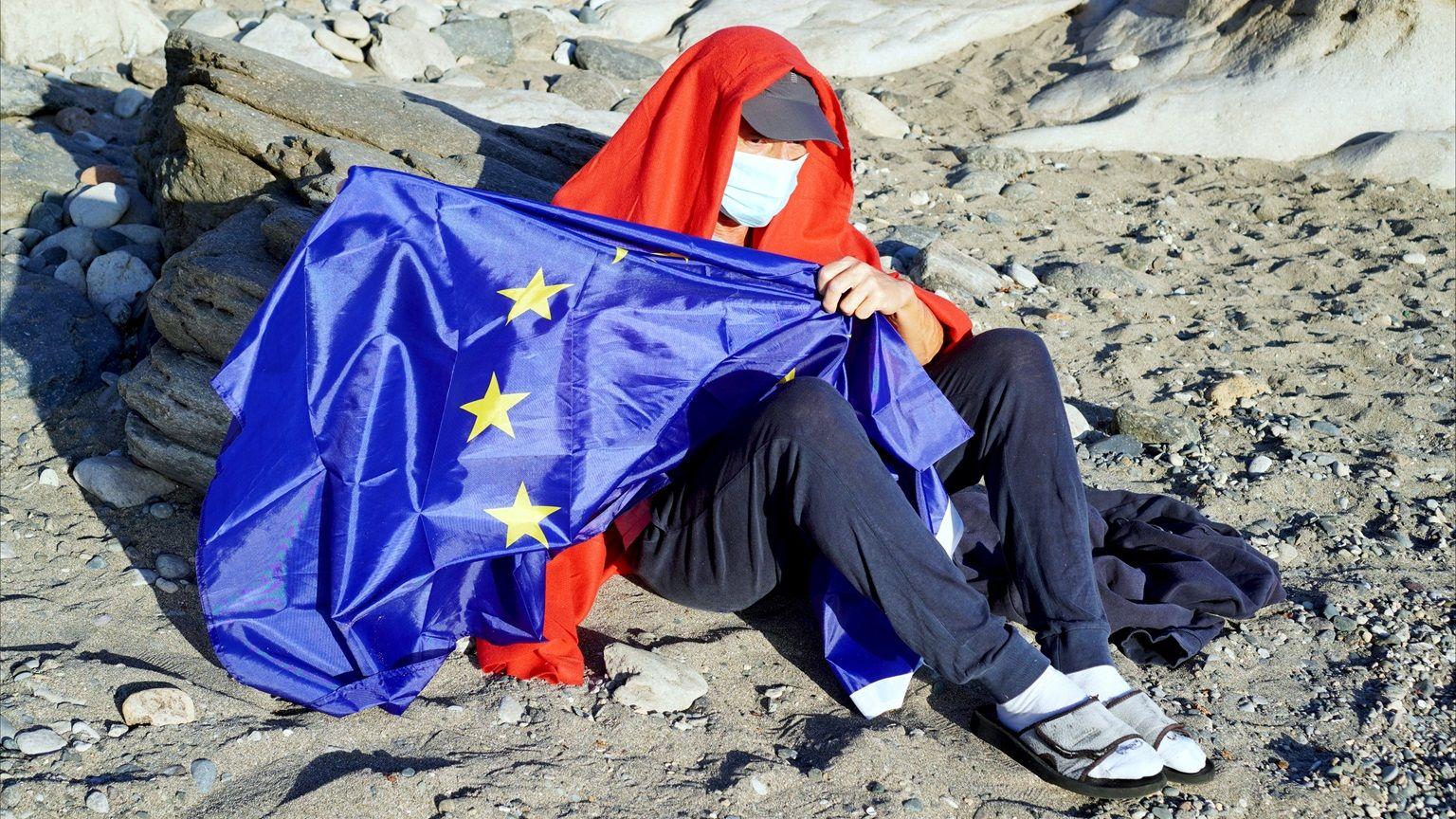 Migrante porta la bandera de la Unión Europea. 