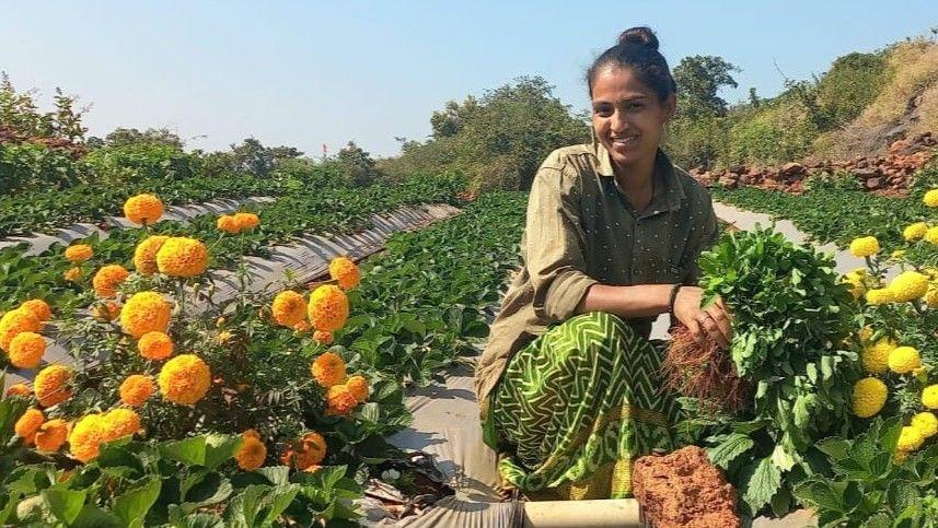 Sheetal Danavle crouches in a field, surrounded by flowers.