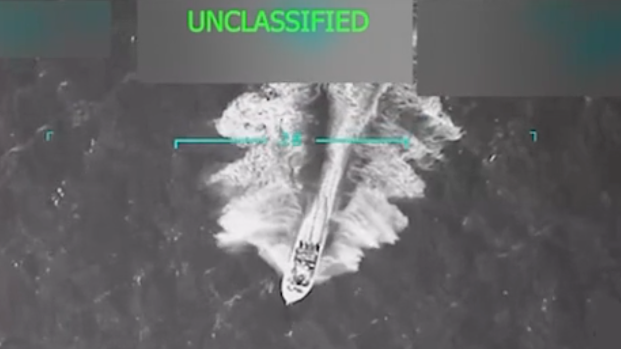 Un pequeño barco atraviesa el océano, en una imagen aérea en blanco y negro. 