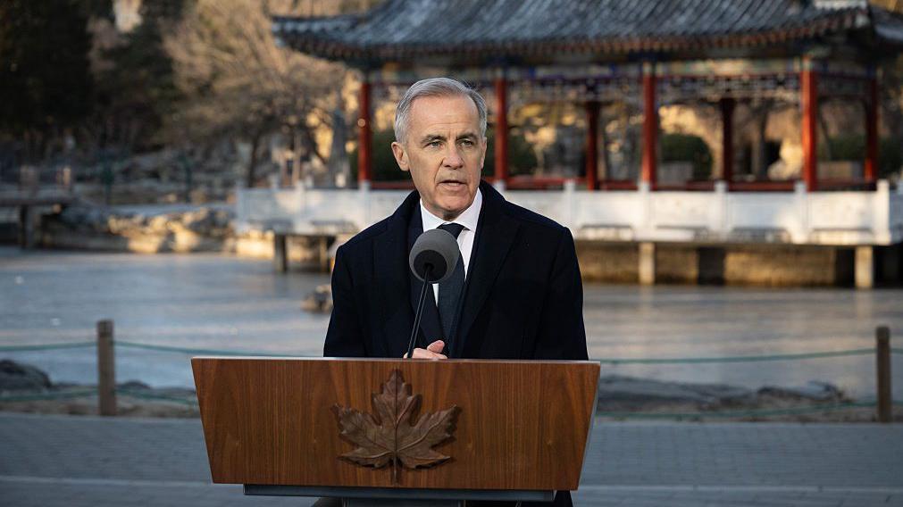 El primer ministro canadiense, Mark Carney, habla tras un atril con un edificio tradicional chino en una reciente visita a Pekín. 