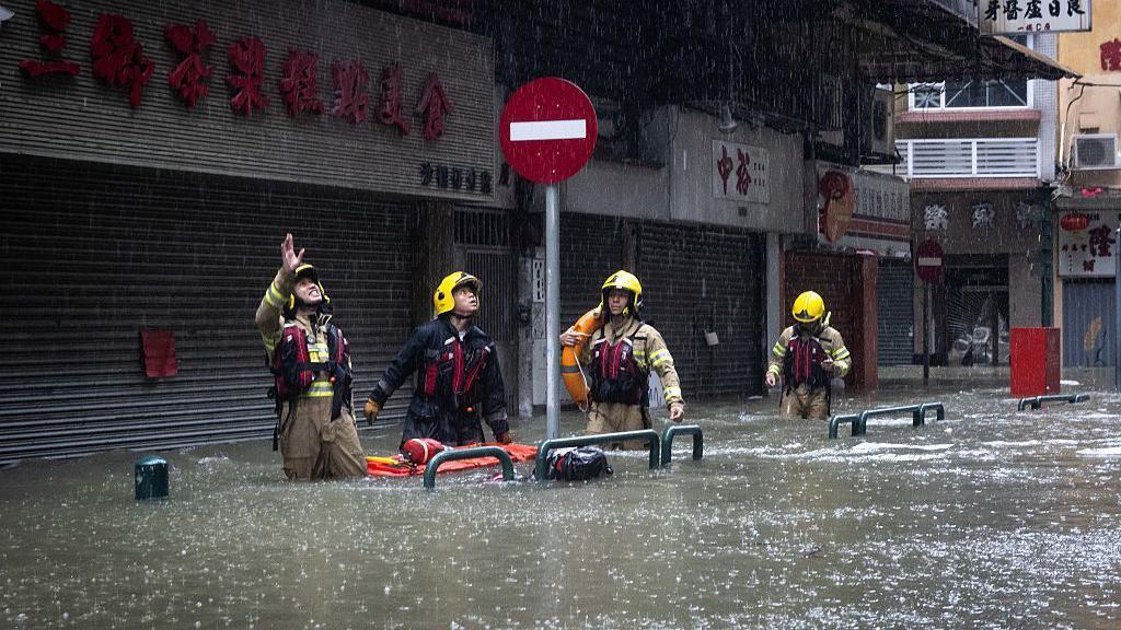 Bomberos caminan por las calles con el agua hasta la cintura.