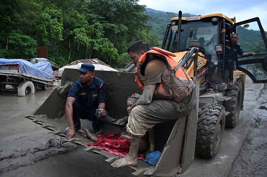 Un grupo de supervivientes sobre una pala mecánica utilizada para despejar caminos.