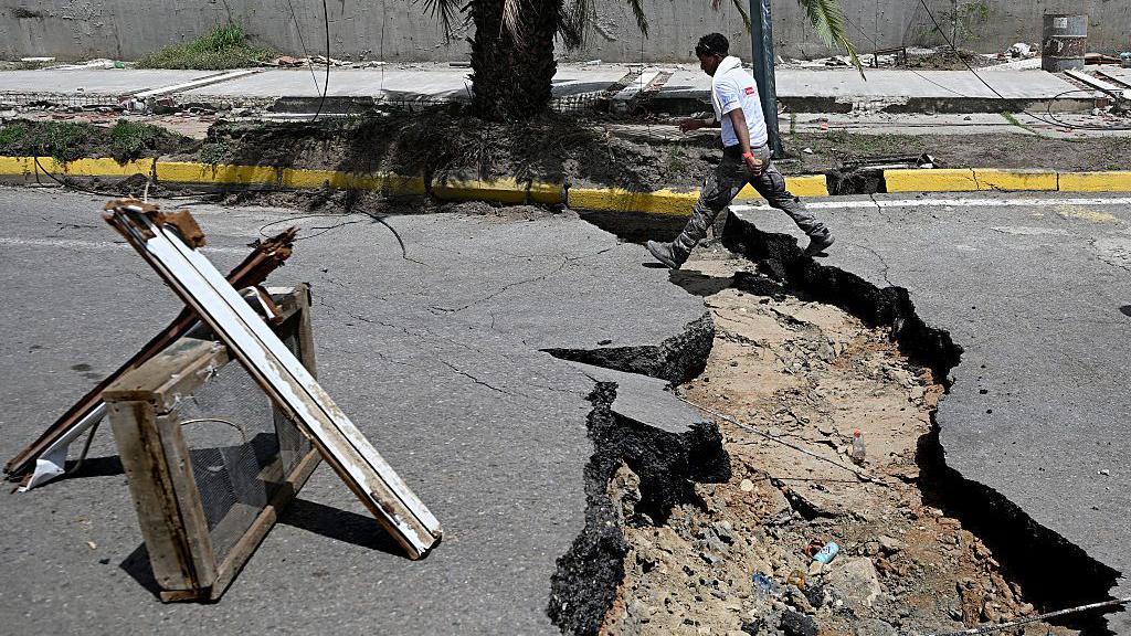 Un hombre camina en una calle agrietada después de un doble terremoto, en Los Corales, estado de La Guaira, a unos 38 km al noroeste de Caracas, el 25 de junio de 2026.