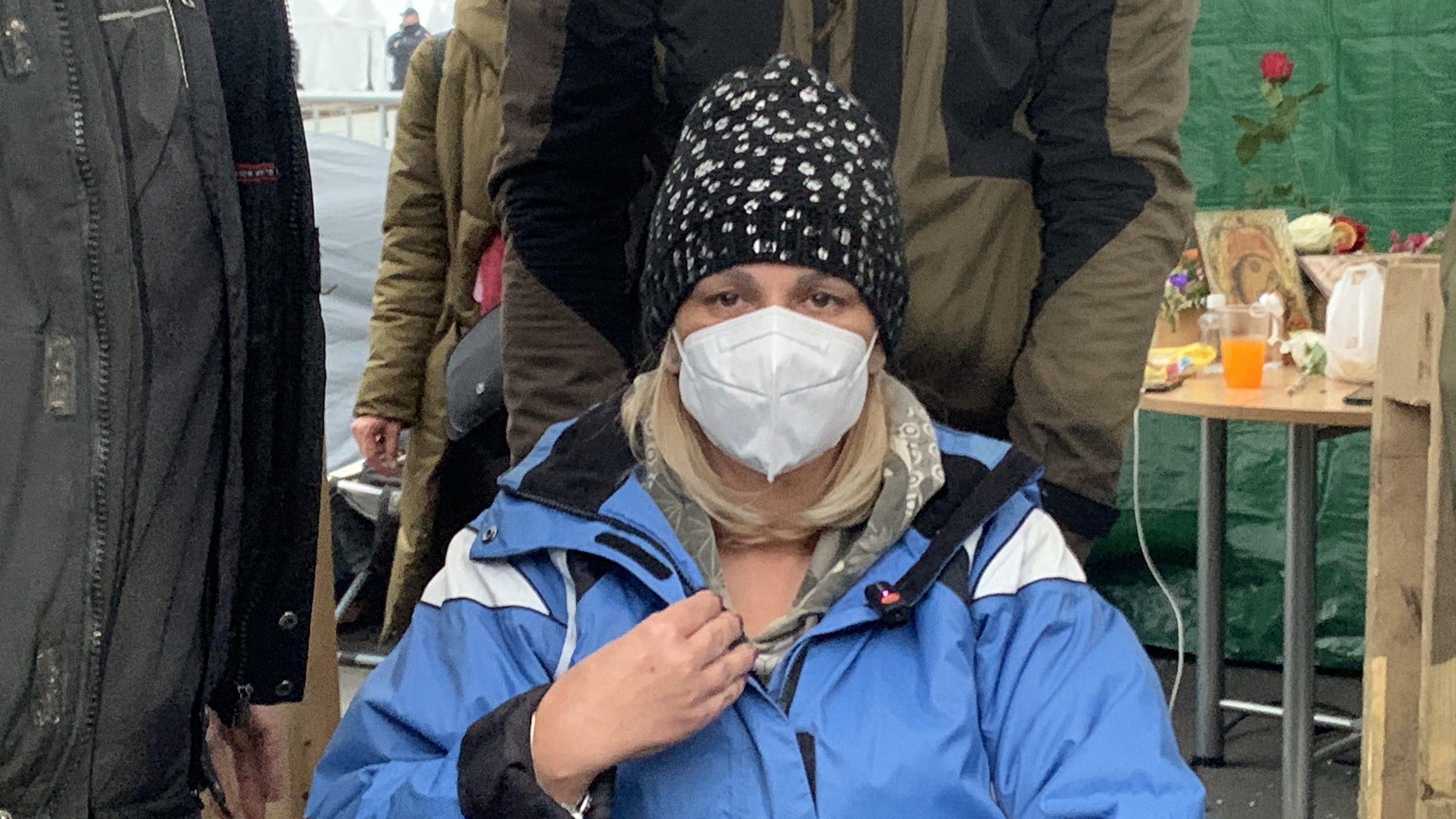 Dijana Hrka sa maskom na licu, sedi u kolicima, ima plavu jaknu i šarenu kapu na glavi