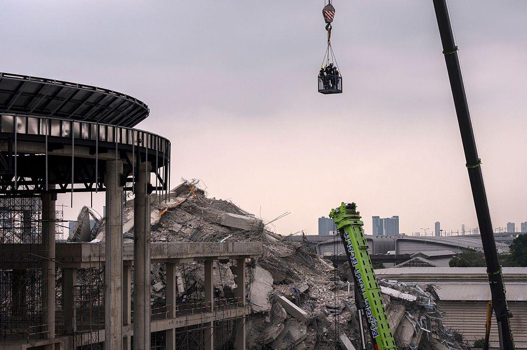 曼谷一棟在建建築倒塌現場，搜救人員被起重機吊起
