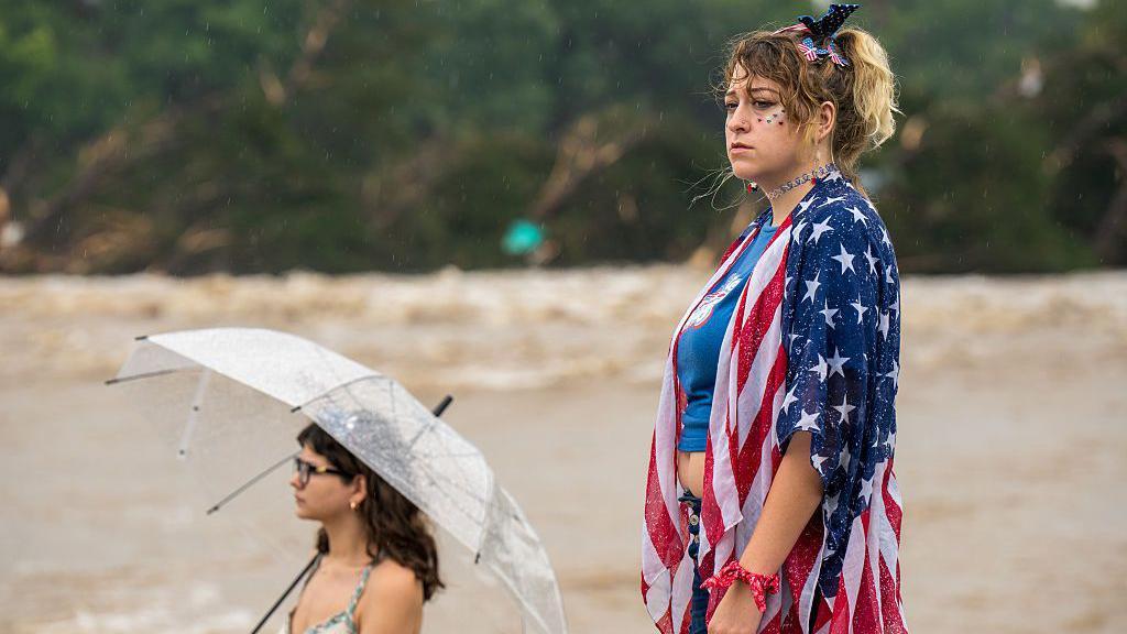 Mulheres observam as águas da enchente nas margens do Rio Guadalupe em 4 de julho de 2025 em Kerrville, Texas