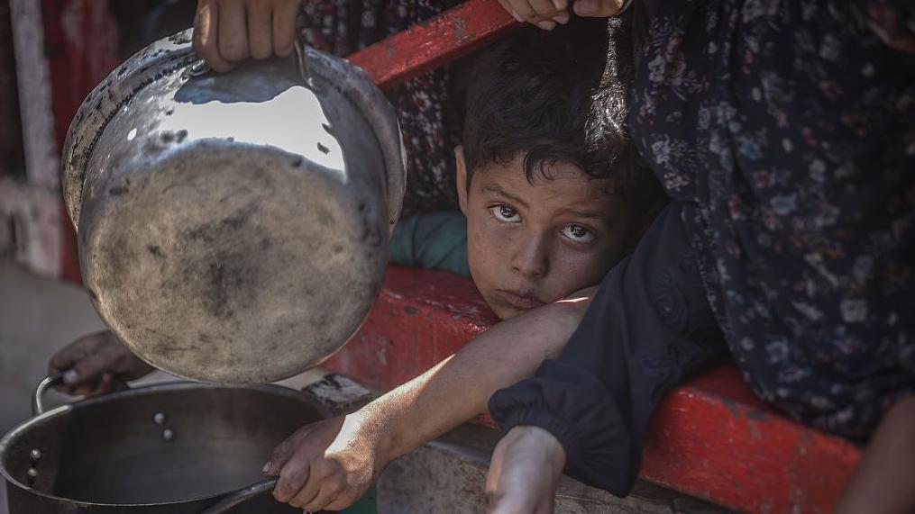 Un niño espera recibir comida en Gaza.