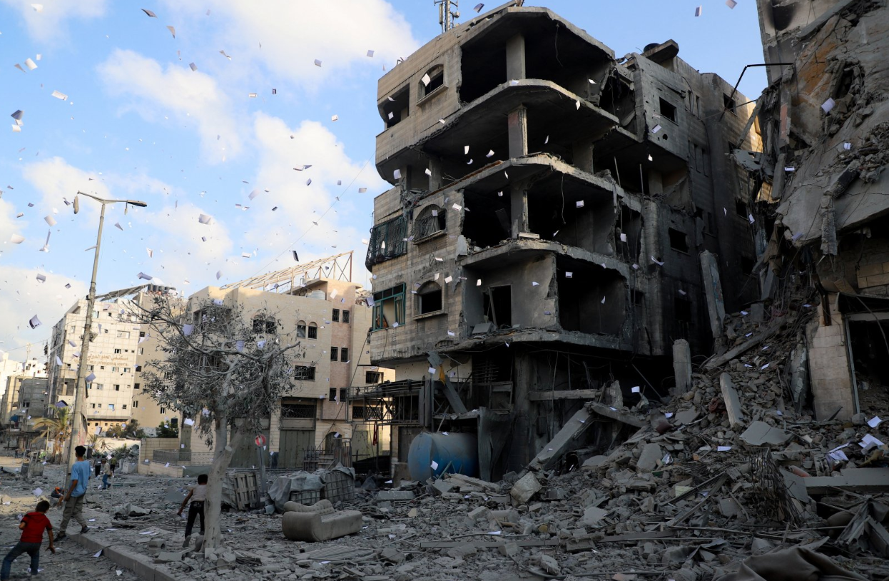 Gazatíes cerca de edificios destruidos en Gaza