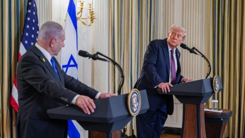 Netanyahu e Trump se olham, cada um de seu palanque em salão com bandeiras dos respectivos países