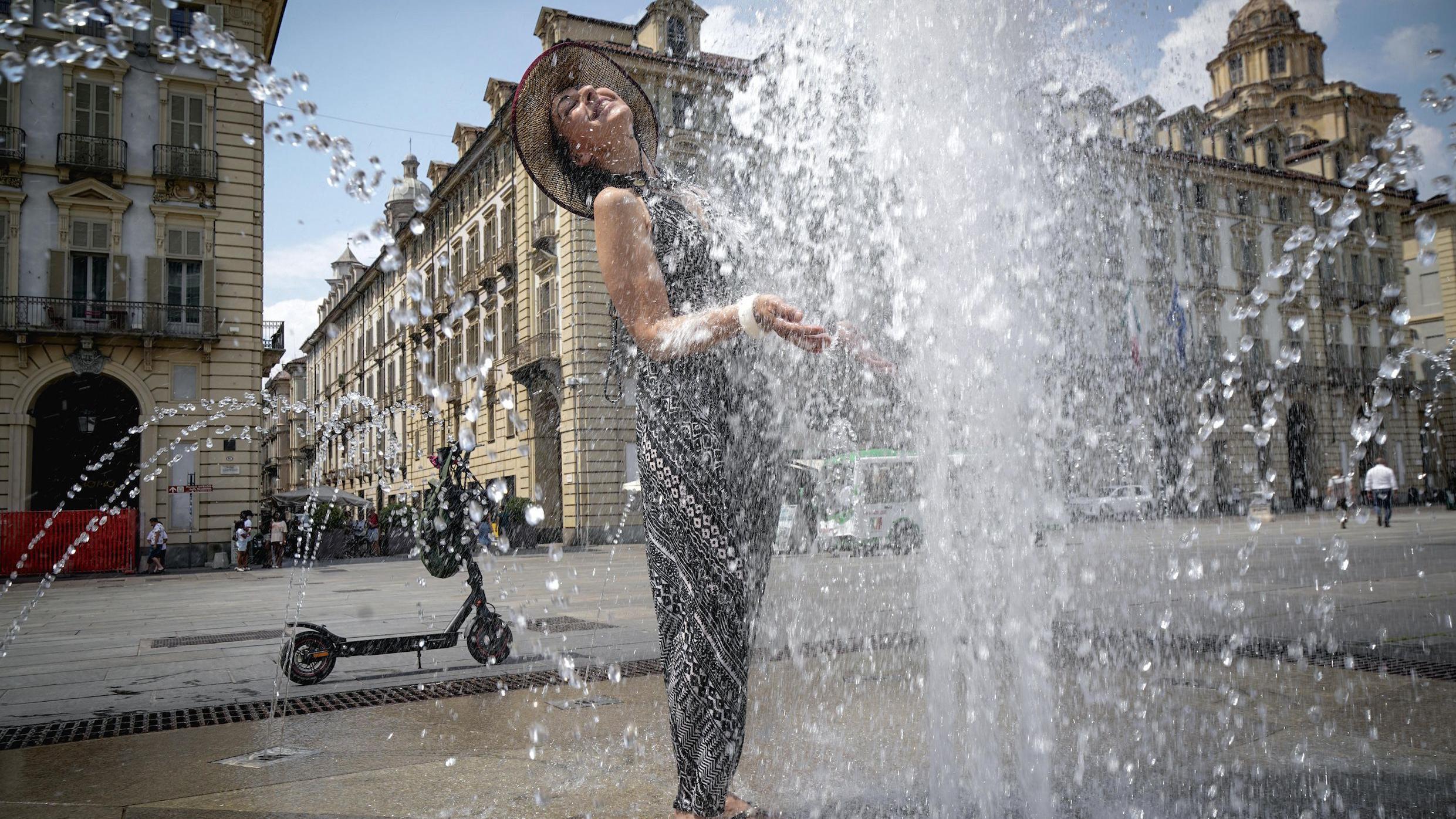 Žena se rashlađuje na trgu u Torinu, na severu Italije