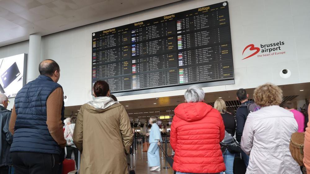 putnici gledaju u raspored letova na aerodromu u Briselu