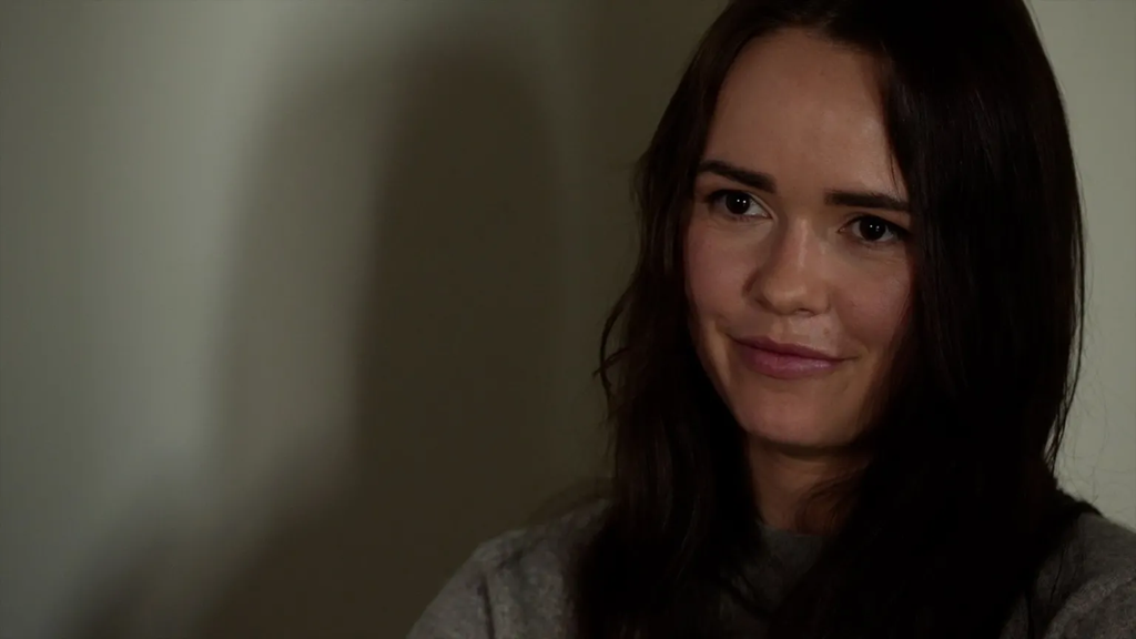 إيرينا تيريك من فاير بوينت، بخلفية بيضاء مائلة للصفرة، وشعر أسود طويل وسترة رمادية.