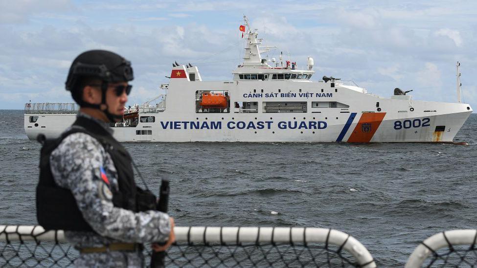 A member of the Philippine Coast Guard personnel stands guard aboard the Gabriela Silang ship as a Vietnamese Coast Guard ship sails past during a joint maritime exercise off Bataan in the disputed South China Sea on August 9, 2024. 