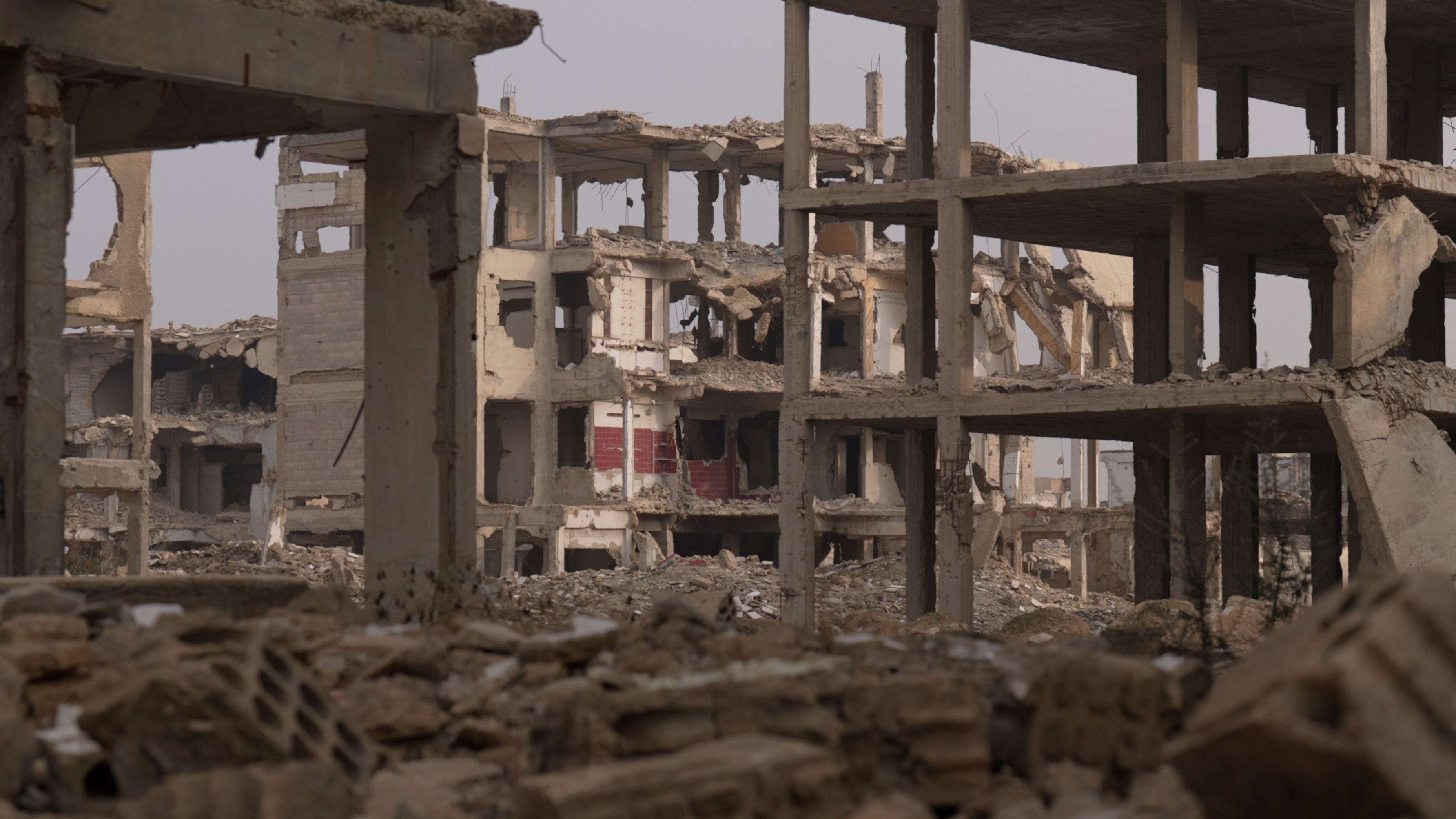 هياكل خرسانية لمبانٍ سكنية مدمرة، محاطة بالأنقاض، في جوبر، وهو حيّ يقع على مشارف دمشق