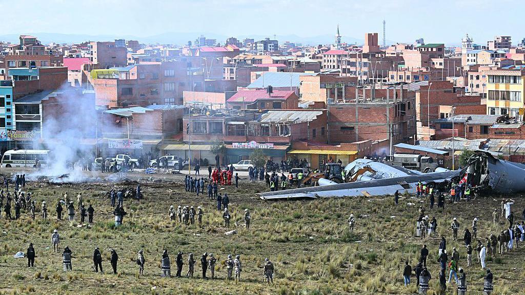 El avión partido en dos rodeado de gente en el lugar del accidente. 