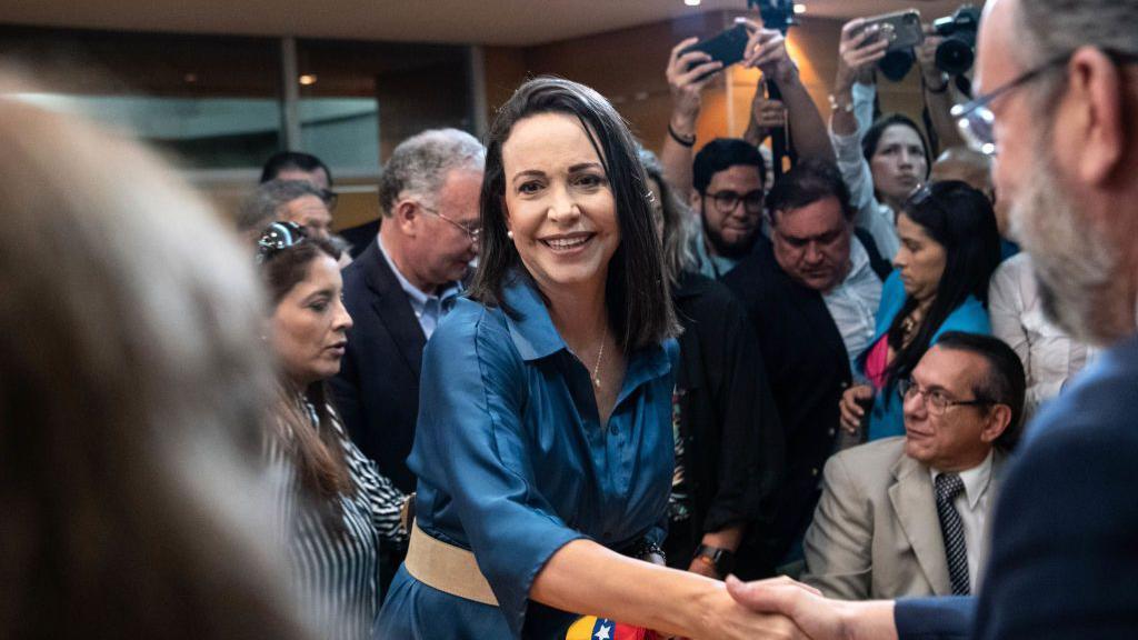 María Corina Machado saludo a un grupo de personas. Se le ve soreir. 