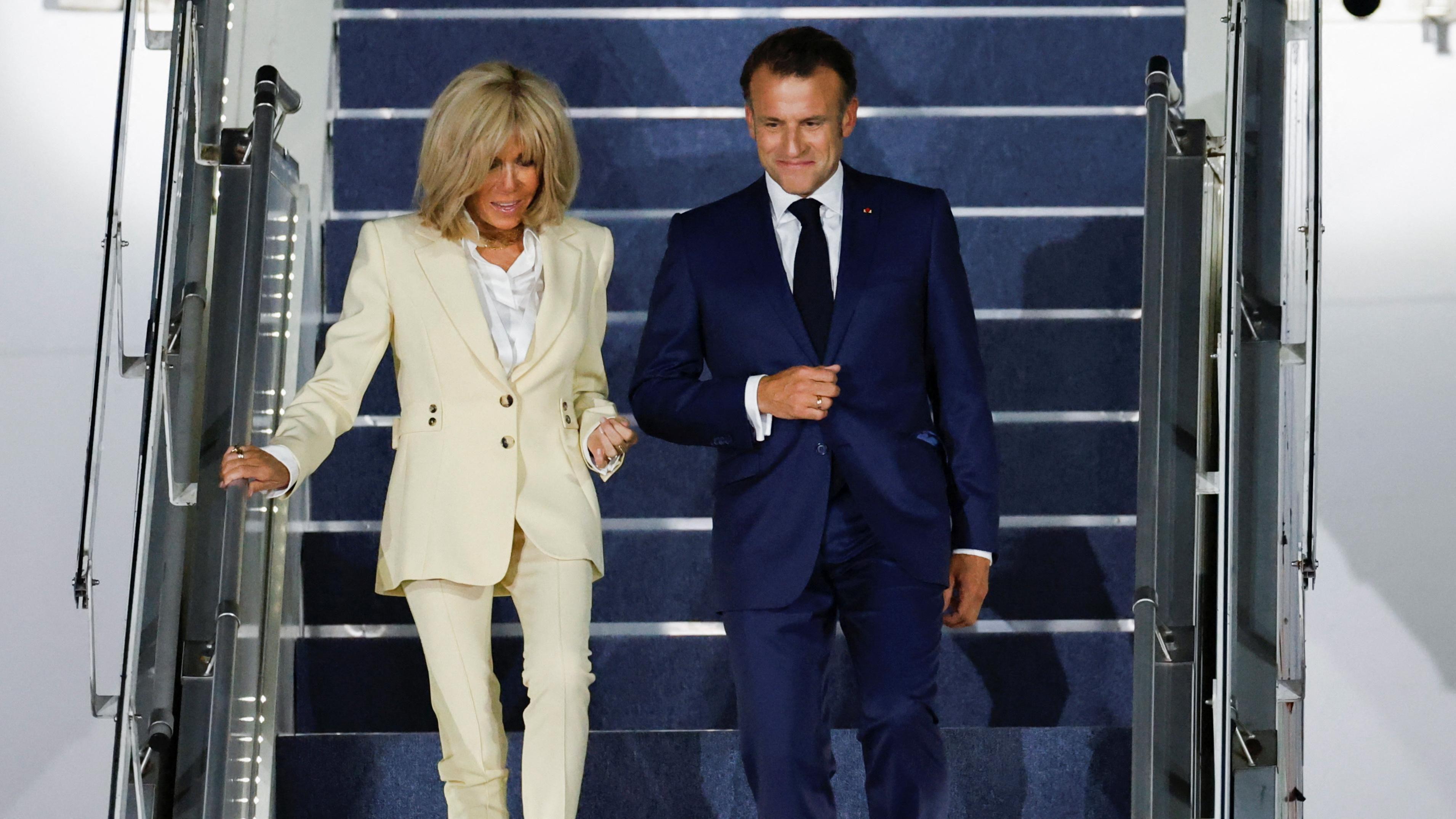 صورة للرئيس الفرنسي ماكرون وزوجته بريجيت ينزلان من سلم طائرة. 